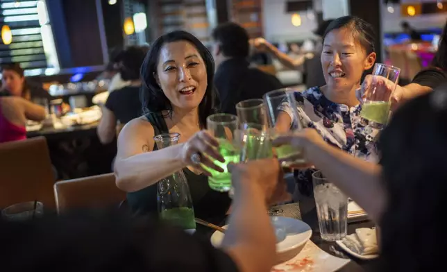 Joy Alessi, left, and Leah Elmquist toast during a dinner with fellow adoptees Sunday, June 23, 2024, in Las Vegas. Alessi and Elmquist have found strength in the community of adoptees who only learned as adults they were never citizens. (AP Photo/David Goldman)