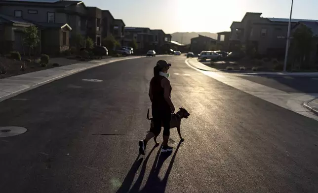 Joy Alessi walks her dog, Phoenix, through her neighborhood Tuesday, June 25, 2024, in Henderson, Nev. Alessi is one of thousands of children adopted from abroad by American parents, many of them military service members, who were left without citizenship by loopholes in American law that Congress has been aware of for decades, yet remains unwilling to fix. (AP Photo/David Goldman)