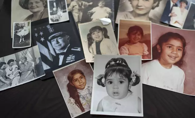 Childhood photos of Buttons are displayed along with a picture of her father, a WWII Air Force veteran, at left, and additional family photos, Monday, June 24, 2024, in Henderson, Nev. "My dad died thinking, 'I raised my daughter. I did my part,' but not knowing it put me on a path of instability and fear," she said. (AP Photo/David Goldman)