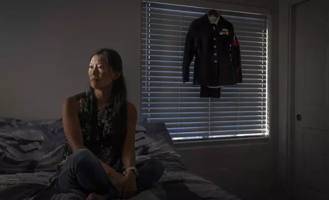 Leah Elmquist, sits for a portrait as her Navy uniform hangs in her home, Wednesday, June 26, 2024, in Las Vegas. Elmquist was among thousands of adoptees left without citizenship by loopholes in American law. She excelled in the military, but wasn't eligible for certain security clearances. She left after a decade, then laid low, fearing deportation. (AP Photo/David Goldman)