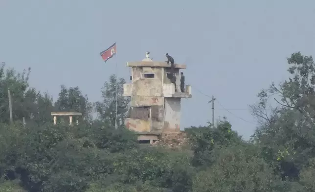 FILE - North Korean soldiers work at the North's military guard post as a North Korean flag flutters in the wind, are seen from Paju, South Korea, near the border with North Korea, Thursday, Oct. 10, 2024. (AP Photo/Ahn Young-joon, File)