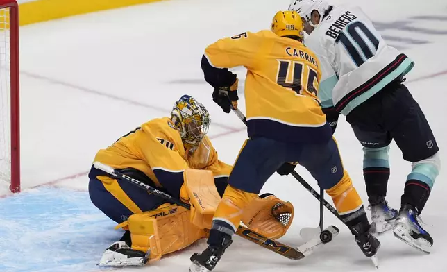 Nashville Predators goaltender Juuse Saros (74) and right wing Michael McCarron (47) block a shot on goal by Seattle Kraken center Matty Beniers (10) during the third period of an NHL hockey game Tuesday, Oct. 15, 2024, in Nashville, Tenn. (AP Photo/George Walker IV)