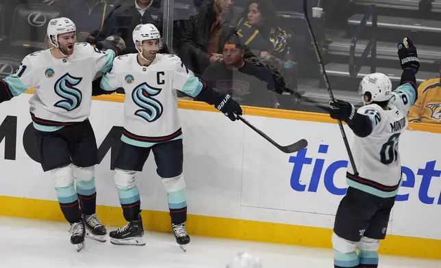 Seattle Kraken right wing Jordan Eberle, center, celebrates his goal with center Shane Wright (51) and defenseman Brandon Montour (62) during the third period of an NHL hockey game against the Nashville Predators, Tuesday, Oct. 15, 2024, in Nashville, Tenn. (AP Photo/George Walker IV)