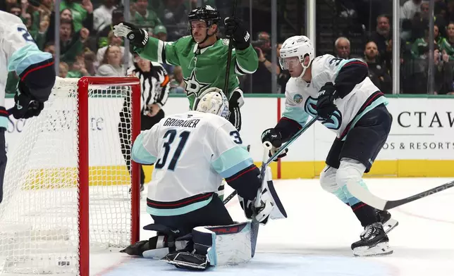 Dallas Stars center Sam Steel (18) reacts after scoring against Seattle Kraken goaltender Philipp Grubauer (31) and defenseman Will Borgen (3) in the first period during an NHL hockey game Sunday, Oct. 13, 2024, in Dallas. (AP Photo/Richard W. Rodriguez)