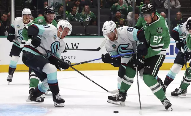 Dallas Stars left wing Mason Marchment (27) shoots against Seattle Kraken defensemen Ryker Evans (41) and Adam Larsson (6) in the first period during an NHL hockey game Sunday, Oct. 13, 2024, in Dallas. (AP Photo/Richard W. Rodriguez)