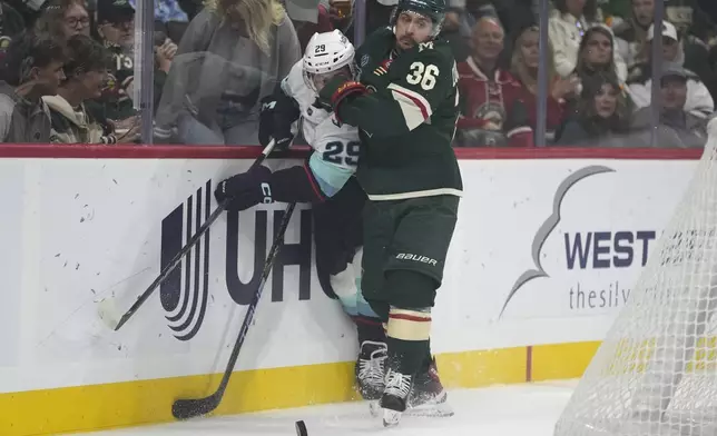 Seattle Kraken defenseman Vince Dunn (29) and Minnesota Wild right wing Mats Zuccarello (36) battle for the puck during the first period of an NHL hockey game, Saturday, Oct. 12, 2024, in St. Paul, Minn. (AP Photo/Abbie Parr)