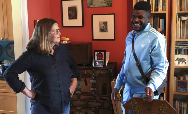 CORRECTS SPELLING OF LAST NAME Cabrel Ngounou, right, a refugee from Cameroon, talks with his sponsor Lori Ostlund in her home in San Francisco, Tuesday, Sept. 17, 2024. (AP Photo/Terry Chea)