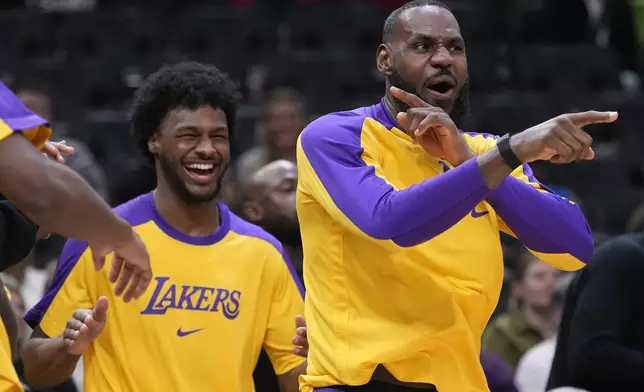 Los Angeles Lakers' LeBron James and Bronny James react on the bench during the second half of an NBA preseason basketball game against the Milwaukee Bucks Thursday, Oct. 10, 2024, in Milwaukee. (AP Photo/Morry Gash)