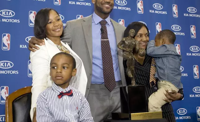 FILE - Cleveland Cavaliers forward and NBA Most Valuable Player LeBron James, center, stands with his family, girfriend, Savannah Brinson, left, in white, son, LeBron Jr., foreground left, James mother Gloria, right, holding James son Bryce, after the NBA MVP award ceremony for James on the University of Akron campus in Akron, Ohio, Sunday, May 2, 2010. (AP Photo/Phil Long, File)