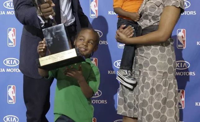 FILE - After accepting the NBA Most Valuable Player award during a ceremony at James' alma mater, Akron St. Vincent-St. Mary High School, in Akron, Ohio, Monday, May 4, 2009, Cleveland Cavaliers LeBron James hands the trophy to his son Lebron Jr., 4, as James girlfriend Savannah Brinson and their youngest son Bryce look on. (AP Photo/Amy Sancetta, File)