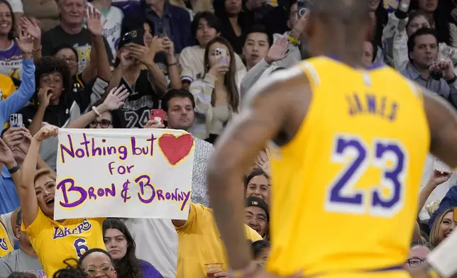 FILE - A fan holds up a sign for Los Angeles Lakers forward LeBron James, right, and his son Bronny during the second half of an NBA preseason basketball game against the Phoenix Suns Thursday, Oct. 19, 2023, in Thousand Palms, Calif. (AP Photo/Mark J. Terrill, File)