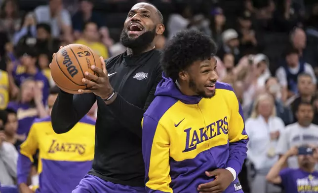 FILE - Los Angeles Lakers forward LeBron James, left, and guard Bronny James warm up before a preseason NBA basketball game against the Phoenix Suns, Sunday, Oct. 6, 2024, in Palm Desert, Calif. (AP Photo/William Liang, File)