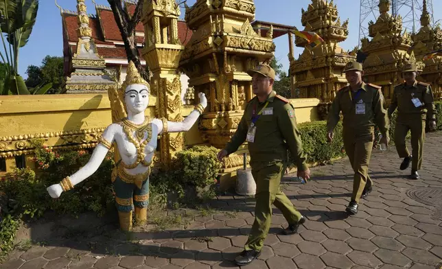 Laos policemen walk in front of Phon Tha Ya Ram Temple in Vientiane, Laos, Monday, Oct. 7, 2024. (AP Photo/Sakchai Lalit)