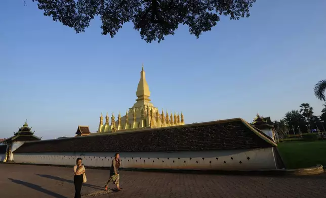 Lao peoples walks outside Pha That Luang T temple in Vientiane, Laos, Monday, Oct. 7, 2024. (AP Photo/Sakchai Lalit)