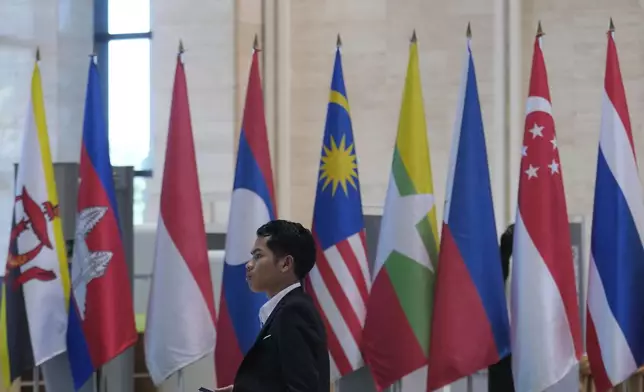 An officer walks in front of flags of nations participating in the meetings of the Association of Southeast Asian Nations (ASEAN) at the national convention center in Vientiane, Laos, Monday, Oct. 7, 2024. (AP Photo/Sakchai Lalit)