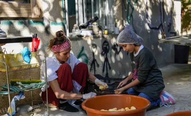 Volunteers prepare meals at a women's art center that was turned into a kitchen for displaced people who fled southern Lebanon amid the ongoing Hezbollah-Israel war, in the town of Aqaibe, northern Lebanon, Thursday, Oct. 24, 2024. (AP Photo/Hassan Ammar)