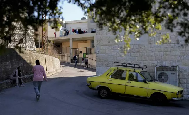 Displaced people who fled southern Lebanon with their families during the ongoing Hezbollah-Israel war walk outside a school in the village of Ebrine, northern Lebanon, Thursday, Oct. 24, 2024. (AP Photo/Hassan Ammar)