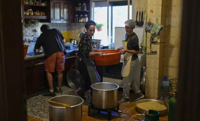 Volunteers prepare meals at a women's art center that was turned into a kitchen for displaced people who fled southern Lebanon amid the ongoing Hezbollah-Israel war, in the town of Aqaibe, northern Lebanon, Thursday, Oct. 24, 2024. (AP Photo/Hassan Ammar)