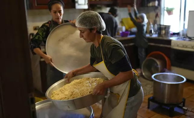 Volunteers prepare meals at a women's art center that was turned into a kitchen for displaced people who fled southern Lebanon amid the ongoing Hezbollah-Israel war, in the town of Aqaibe, northern Lebanon, Thursday, Oct. 24, 2024. (AP Photo/Hassan Ammar)