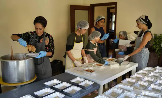 Volunteers prepare meals at a women's art center that was turned into a kitchen for displaced people who fled southern Lebanon amid the ongoing Hezbollah-Israel war, in the town of Aqaibe, northern Lebanon, Thursday, Oct. 24, 2024. (AP Photo/Hassan Ammar)