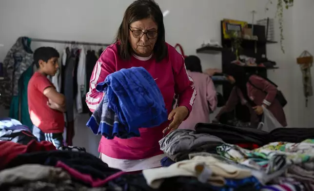 Displaced people select winter clothes at a women's art center that has turned into a kitchen for displaced people who fled southern Lebanon amid the ongoing Hezbollah-Israel war, in the town of Aqaibe, northern Lebanon, Thursday, Oct. 24, 2024. (AP Photo/Hassan Ammar)