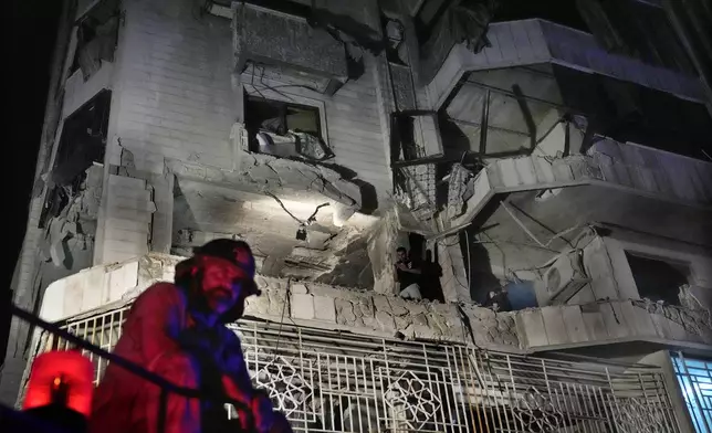 A firefighter stands in front of an apartment hit by an Israeli airstrike, in Beirut, Lebanon, Thursday, Oct. 3, 2024. (AP Photo/Hussein Malla)