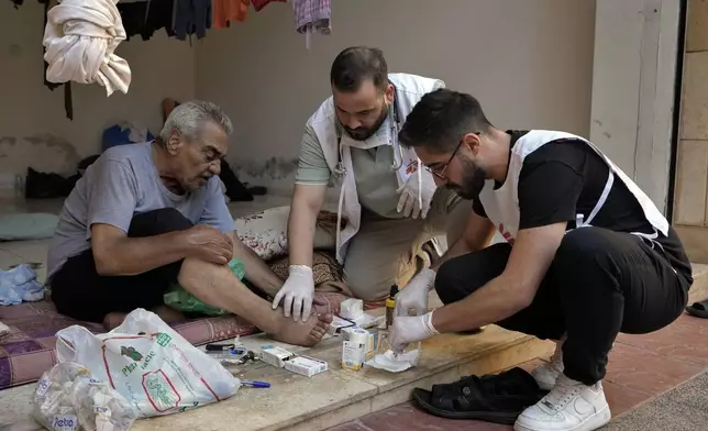 Members of Doctors Without Borders treat a displaced man fleeing the Israeli airstrikes in Dahiyeh, in an empty building complex, in Beirut, Lebanon, Wednesday, Oct. 9, 2024. (AP Photo/Bilal Hussein)