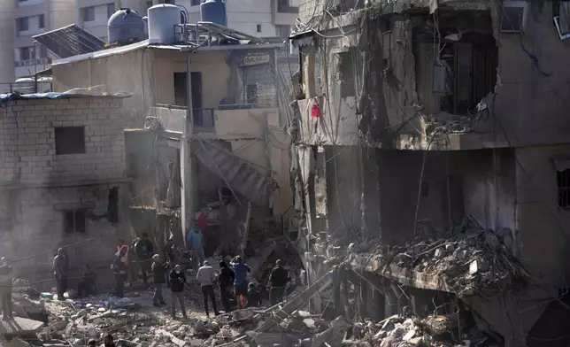 Rescue workers and civilians search for victims between the rubble of destroyed buildings at a popular neighbourhood that was hit Monday night by Israeli airstrikes, south of Beirut, Lebanon, Tuesday, Oct. 22, 2024. (AP Photo/Hussein Malla)