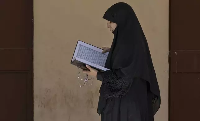 A displaced woman reads a Quran, the Muslim holy book, at a vocational training center run by the U.N. agency for Palestinian refugees, or UNRWA, in the town of Sebline, south of Beirut, Lebanon, Friday, Oct. 4, 2024, after fleeing the Israeli airstrikes in the south. (AP Photo/Bilal Hussein)