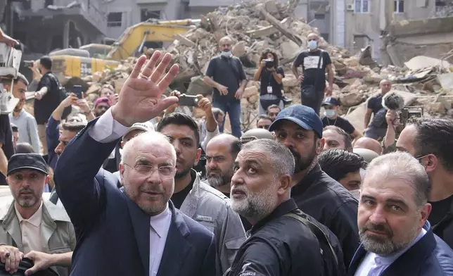 Iran's parliament speaker Mohammad Bagher Qalibaf, left, waves to residents as visit the site of Thursday's Israeli airstrike in Beirut, Lebanon, Saturday, Oct. 12, 2024. (AP Photo/Hassan Ammar)