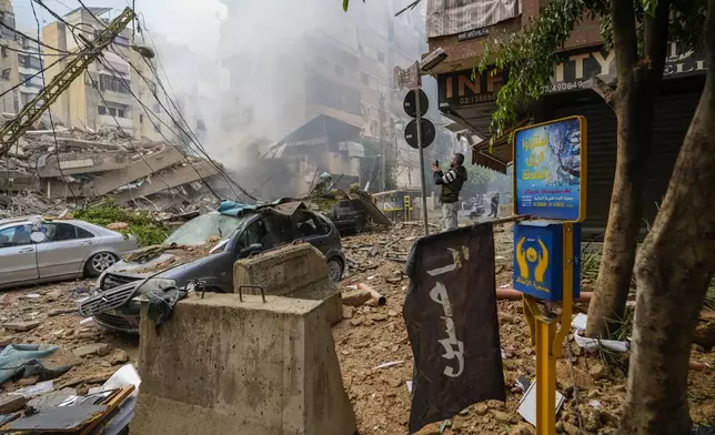 A man documents the damaged buildings at the site of an Israeli airstrike in Beirut's southern suburb, Lebanon, Tuesday, Oct. 1, 2024. (AP Photo/Hassan Ammar)