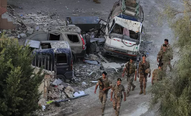 Lebanese army soldiers walk by destroyed cars at the site where an Israeli airstrike hit a building, in Barja village, south of Beirut, Lebanon, Saturday, Oct. 12, 2024. (AP Photo/Mohammed Zaatari)