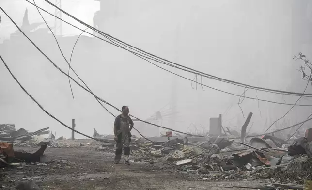 A man walks as smoke rises from destroyed buildings at the site of an Israeli airstrike in Choueifat, southeast of Beirut, Lebanon, Monday, Oct. 7, 2024. (AP Photo/Bilal Hussein)