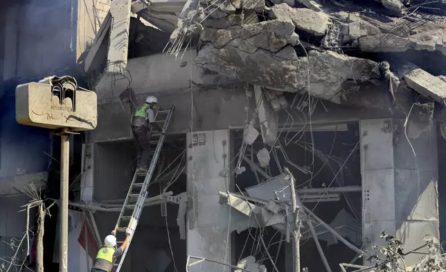 Hezbollah rescue workers search for victims on a destroyed building at commercial street that was hit Saturday night by Israeli airstrikes, in Nabatiyeh town, south Lebanon, Sunday, Oct. 13, 2024. (AP Photo/Mohammed Zaatari)