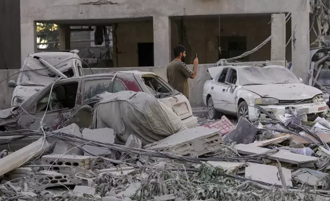 A man documents the damaged buildings at the site of an Israeli airstrike in Dahiyeh, Beirut, Lebanon, Thursday, Oct. 3, 2024. (AP Photo/Hassan Ammar)