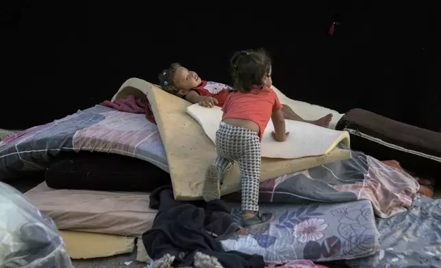 Children play next to their family's tent after fleeing the Israeli airstrikes in Dahiyeh, Beirut, Lebanon, Monday, Oct. 14, 2024. (AP Photo/Bilal Hussein)