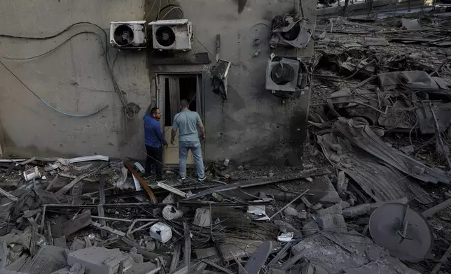 People check the site of an Israeli airstrike in Dahiyeh, Beirut, Lebanon, Sunday, Oct. 6, 2024. (AP Photo/Bilal Hussein)