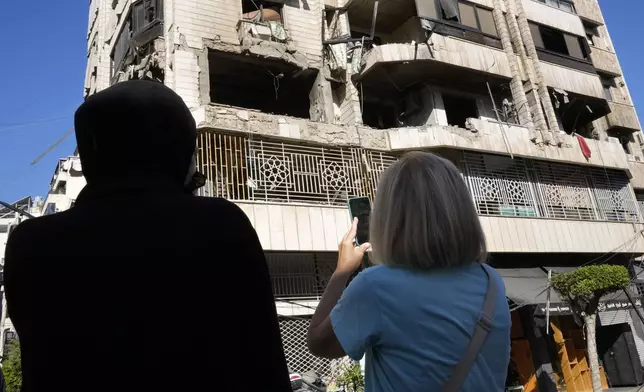 Lebanese women stand in front an apartment in a multistory building hit by Israeli airstrike, in central Beirut, Lebanon, Thursday, Oct. 3, 2024. (AP Photo/Hussein Malla)