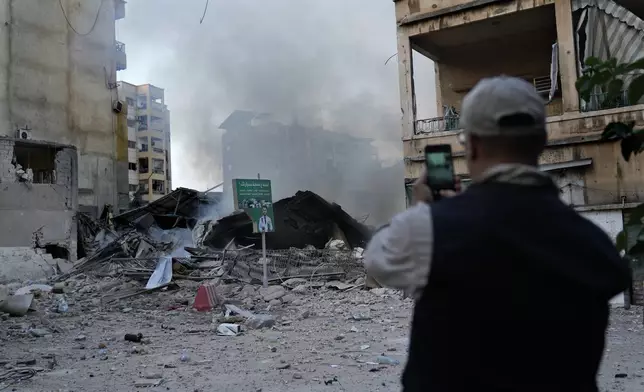 A man takes pictures of a destroyed building hit by Israeli airstrike in Dahiyeh, Beirut, Lebanon, Sunday, Oct. 6, 2024. (AP Photo/Hussein Malla)