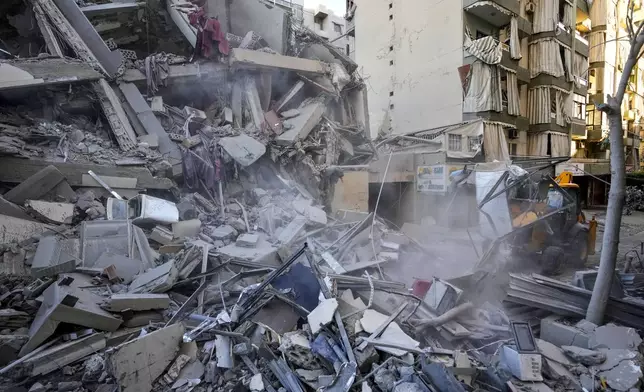 Rescue workers use a bulldozer to remove rubble of destroyed buildings at the site of an Israeli airstrike on Sunday night that hit several branches of the Hezbollah-run al-Qard al-Hassan in Beirut's southern suburb, Lebanon, Monday, Oct. 21, 2024. (AP Photo/Hassan Ammar)