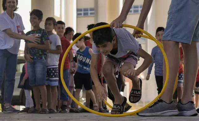 A volunteer of the Russian Cultural Center entertains displaced children at a school in Beirut, Lebanon, Thursday, Oct. 3, 2024, after fleeing the Israeli airstrikes in the south. (AP Photo/Bilal Hussein)