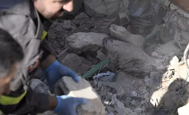 EDS NOTE: GRAPHIC CONTENT - Rescue workers clear the rubble to retrieve a body at the site of a destroyed building hit in an Israeli airstrike on Tuesday night, in Sarafand, southern Lebanon, Wednesday, Oct. 30, 2024. (AP Photo/Bilal Hussein)