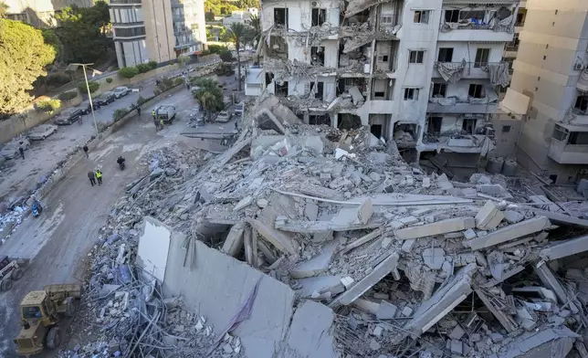 Rescue workers use a bulldozer to remove rubble of destroyed buildings at the site of an Israeli airstrike on Sunday night that hit several branches of the Hezbollah-run Qard al-Hassan Association in Beirut's southern suburb, Lebanon, Monday, Oct. 21, 2024. (AP Photo/Hassan Ammar)