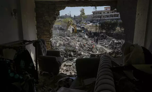 Rescue workers use an excavator to clear the rubble of a destroyed building hit Tuesday night in an Israeli airstrike, as they search for victims, in Sarafand, southern Lebanon, Wednesday, Oct. 30, 2024. (AP Photo/Bilal Hussein)