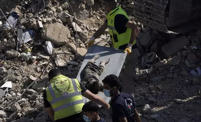 Emergency workers carry the body of a victim found in the rubble of a destroyed building hit Tuesday night in an Israeli airstrike in Sarafand, south Lebanon, Wednesday, Oct. 30, 2024. (AP Photo/Bilal Hussein)