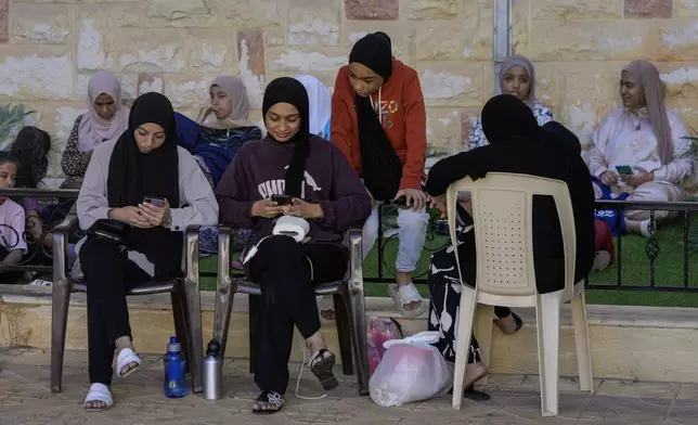 Displaced people sit at a vocational training center run by the U.N. agency for Palestinian refugees, or UNRWA, in the southern town of Sebline, south of Beirut, Lebanon, Friday, Oct. 4, 2024, after fleeing the Israeli airstrikes in the south. (AP Photo/Bilal Hussein)