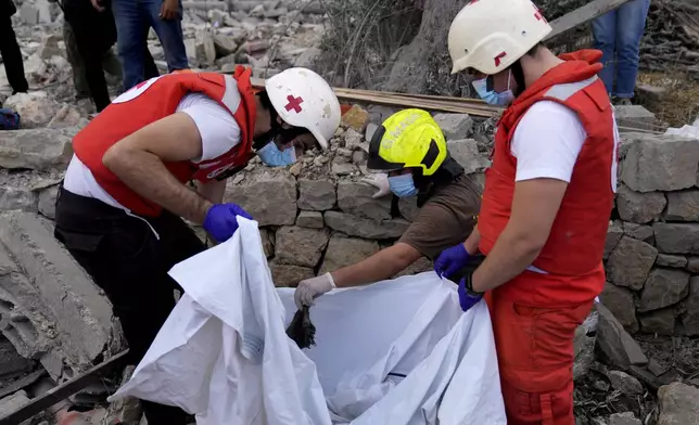 Lebanese Red Cross volunteers and Civil Defence worker remove the remains of killed people from the rubble of a destroyed building at the site of Monday's Israeli airstrike in Aito village, north Lebanon, Tuesday, Oct. 15, 2024. (AP Photo/Hussein Malla)