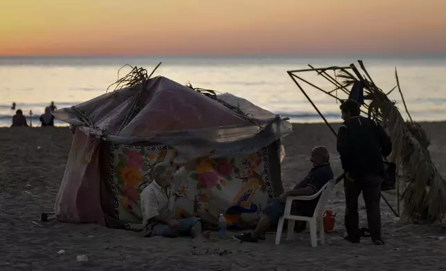 A displaced family sits next to their tent as a temporary shelter at Ramlet al-Baida public beach, after fleeing the Israeli airstrikes in the south, in Beirut, Lebanon, Tuesday, Oct. 8, 2024. (AP Photo/Bilal Hussein)