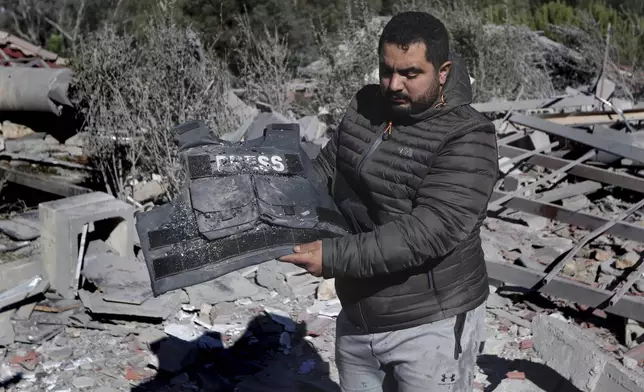 A journalist carries the flack jacket, at the site where an Israeli airstrike hit a compound housing journalists, killing three media staffers from two different news agencies according to Lebanon's state-run National News Agency, in Hasbaya village, southeast Lebanon, Friday, Oct. 25, 2024. (AP Photo/Mohammed Zaatari)