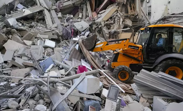 Rescue workers use a bulldozer to remove rubble of destroyed buildings at the site of an Israeli airstrike on Sunday night that hit several branches of the Hezbollah-run al-Qard al-Hassan in Beirut's southern suburb, Lebanon, Monday, Oct. 21, 2024. (AP Photo/Hassan Ammar)